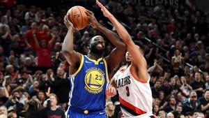 Draymond Green lanza a canasta, superando la defensa de McCollum en el tercer partido