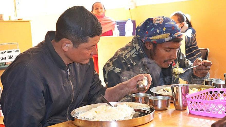 Dos hombres comen dhal bat, un plato típico de Nepal. 