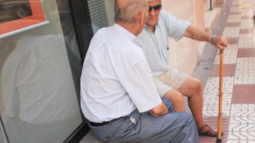 Dos hombres conversan junto a una esquina manchada de orín.