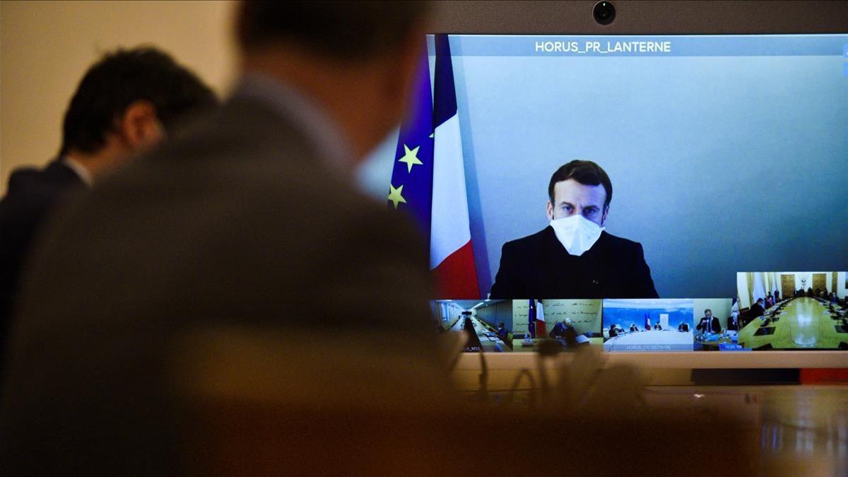 France s President Emmanuel Macron  who tested positive for the coronavirus disease (COVID-19)  is seen on a screen as he attends by video conference a round table for the weekly cabinet meeting of the government at the Army Ministry in Paris  France  December 21  2020   Julien De Rosa Pool via REUTERS