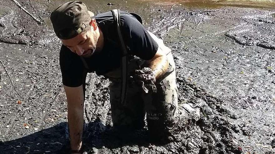 Roberto Díaz, de Aecam, saca al zampullín del fango de la laguna. // Aecam