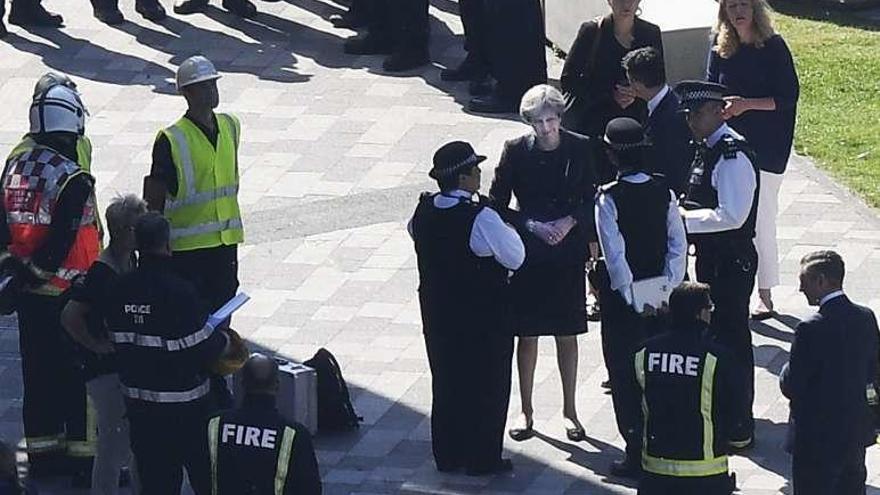 Theresa May charla con agentes de policía y bomberos. // Efe