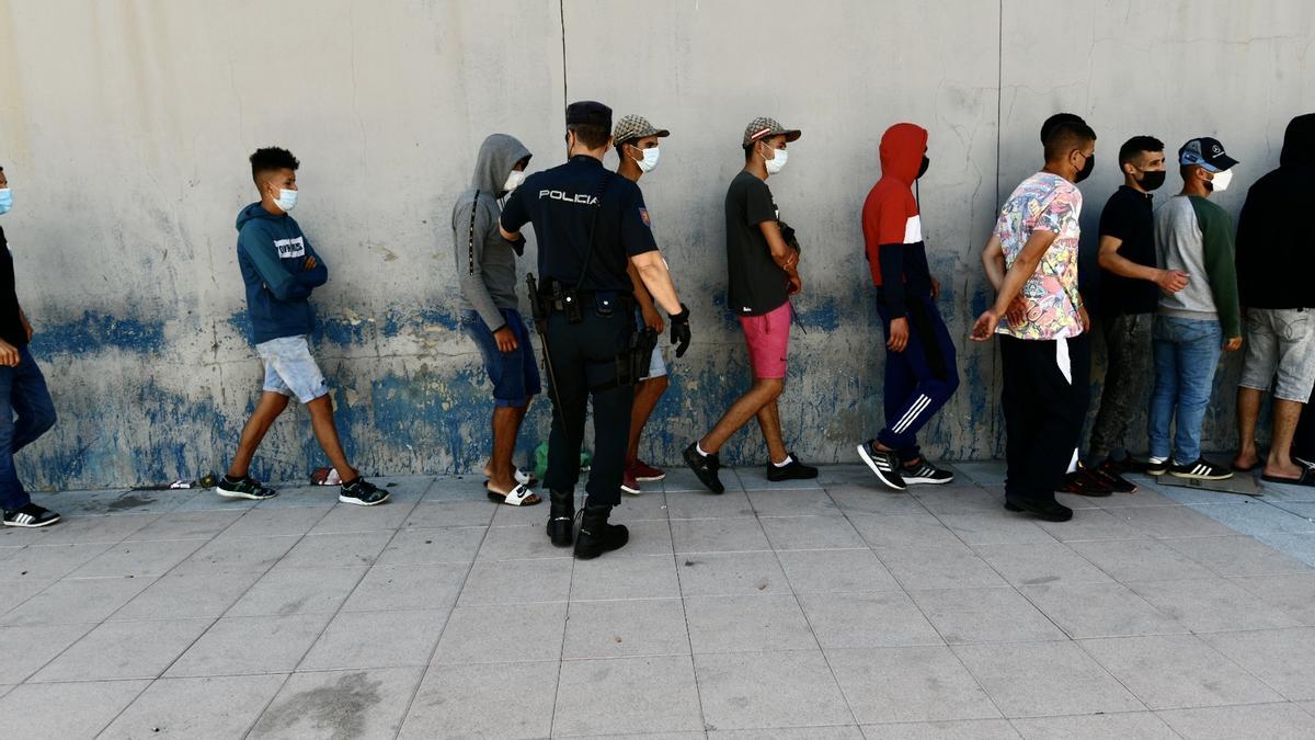 Varios migrantes procedentes de Marruecos hacen cola en las puertas de la frontera de Ceuta.