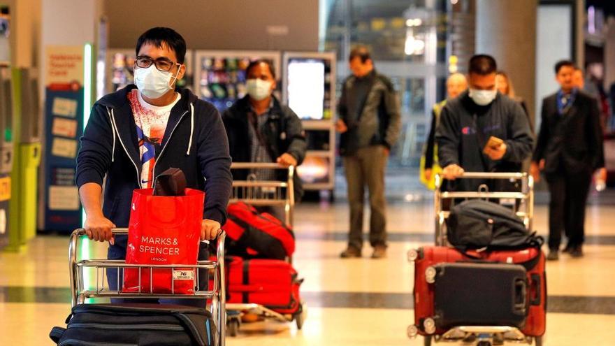 Varios viajeros recién llegados al aeropuerto de Manises se protegen con mascarillas.