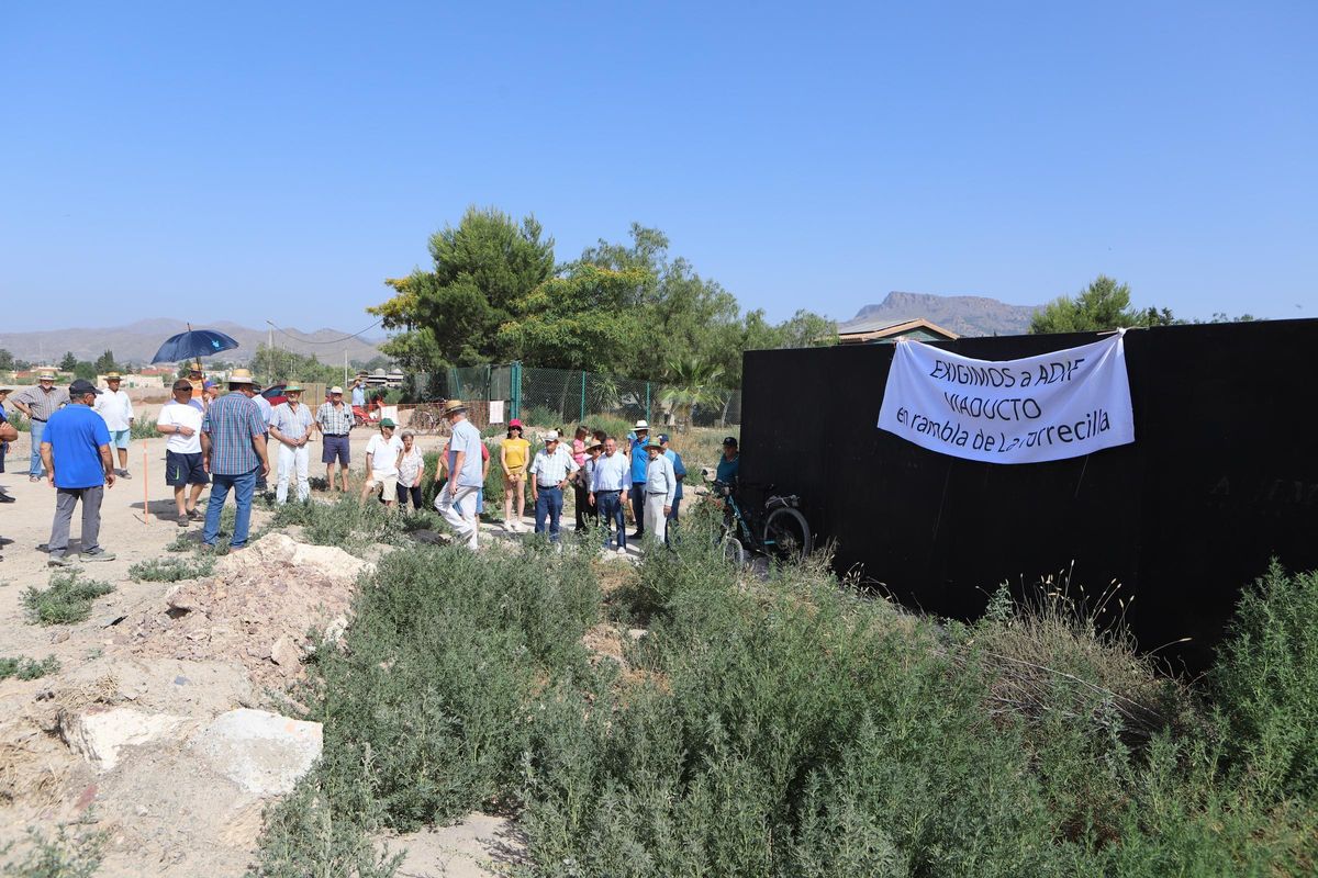 Los vecinos contemplan uno de los pasos de agua ya instalados, hundido en el terreno.