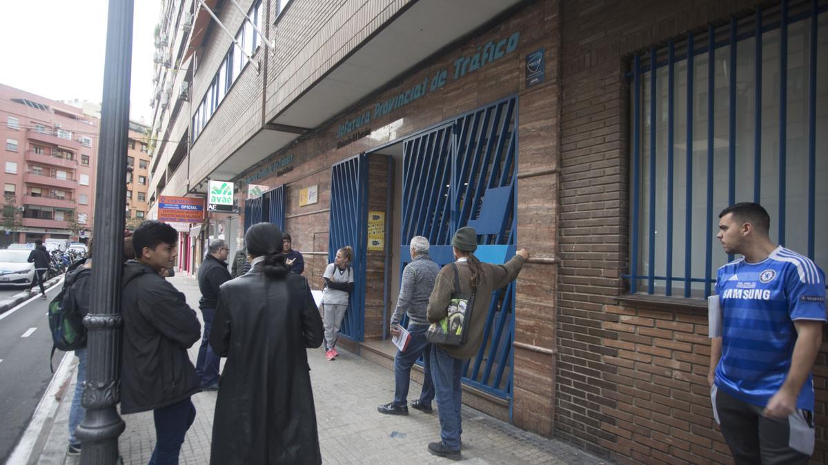 Varias personas esperan en la puerta de la Jefatura Provincial de Tráfico de València, esta semana.