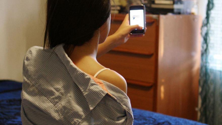 Una joven se toma fotografías con su móvil en su cuarto. |