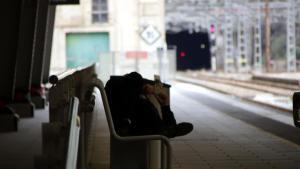 Una persona estirat a un banc de lestació de Portbou
