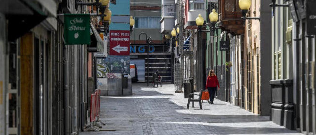 Una mujer camina por una céntrica calle de Las Palmas de Gran Canaria con los comercios cerrados.