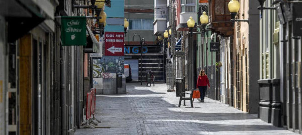 Una mujer camina por una céntrica calle de Las Palmas de Gran Canaria con los comercios cerrados.