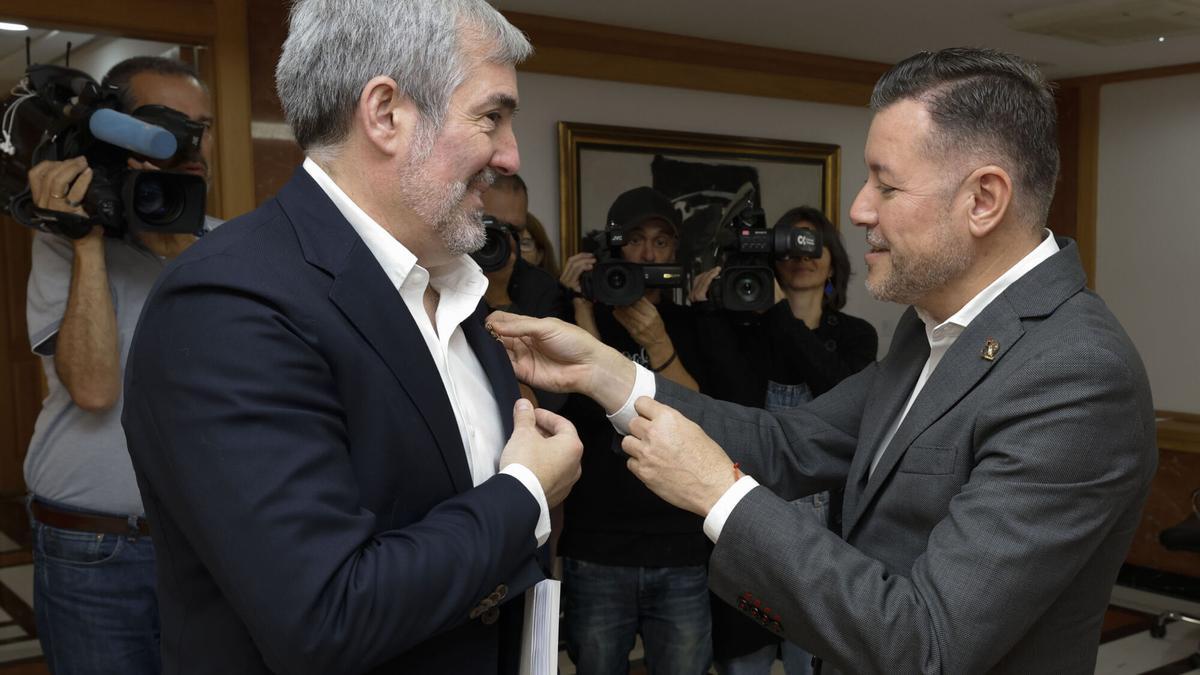 El presidente del Gobierno de Canarias, Fernando Clavijo (i), se reunió este lunes con el presidente de la Mancomunidad del Norte de Gran Canaria, Teodoro Sosa (d), encuentro al que también asisten los once alcaldes de esta comarca. En la imagen, Sosa le coloca a Clavijo el pin conmemorativo del 50 aniversario de la Mancomunidad.