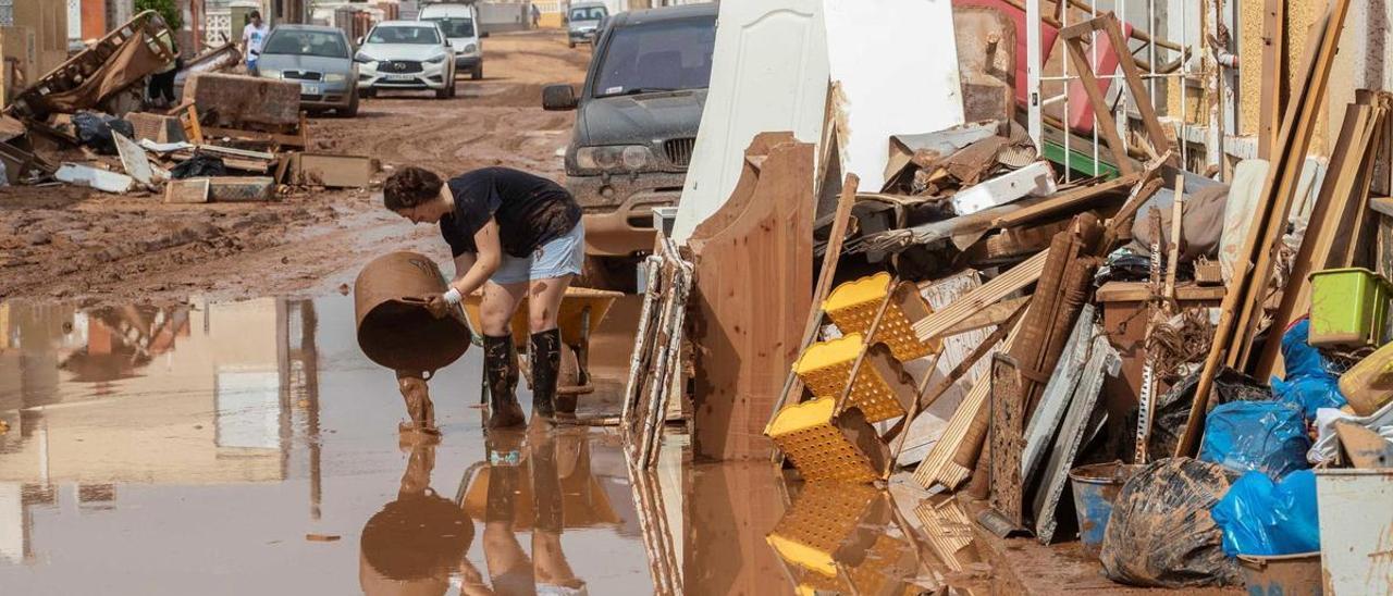 Una mujer vierte lodo en la localidad de Los Nietos, en Cartagena, afectada por las inundaciones de la Región de Murcia de 2019.