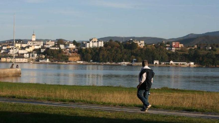 Un vecino caminando por Ribadeo; al fondo Castropol.