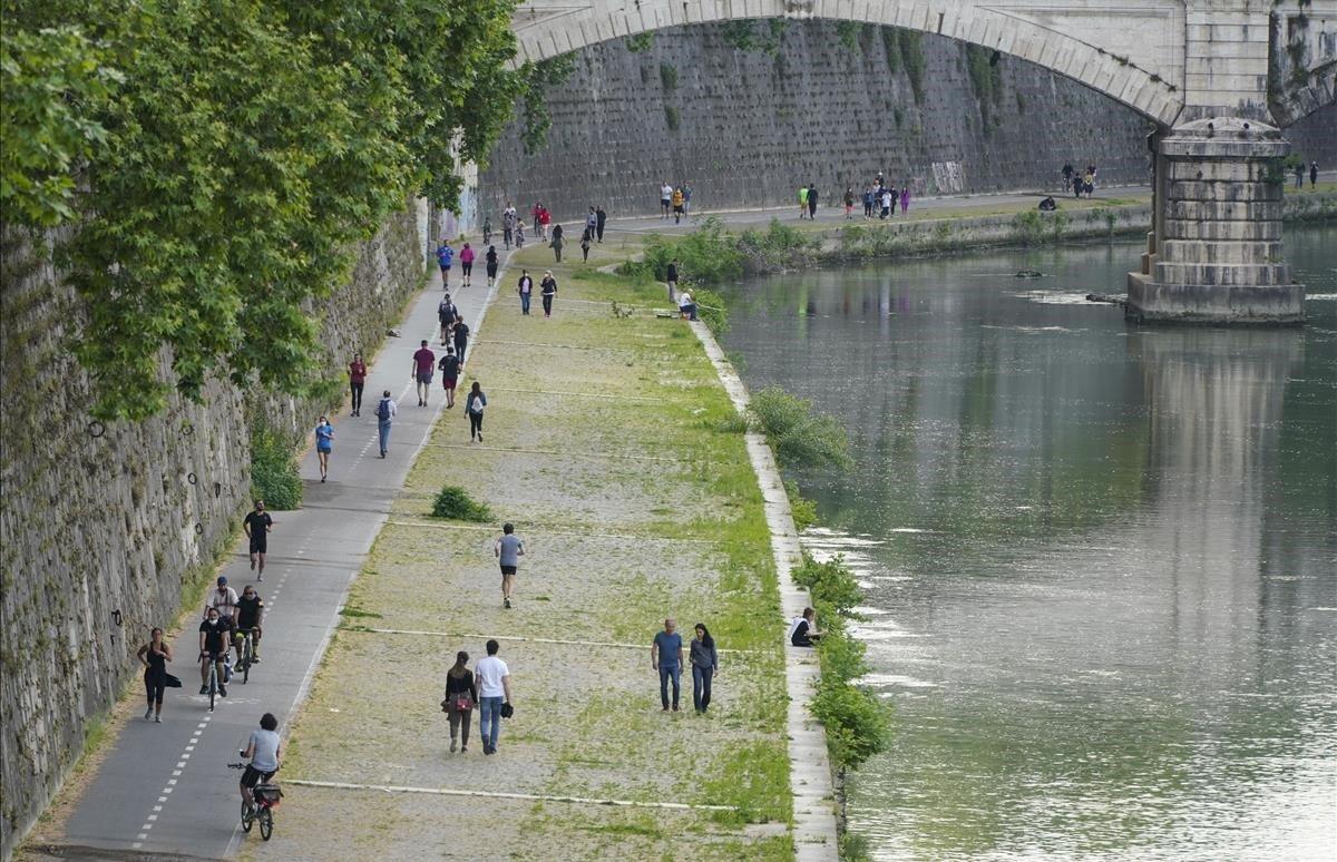 La gente disfruta de un paseo por las riberas del río Tíber.