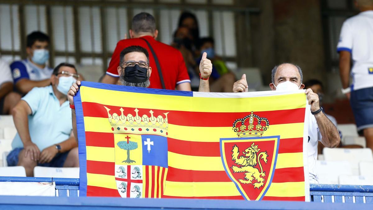 Dos seguidores portan una bandera con los escudos de Aragón y del Real Zaragoza en La Romareda.