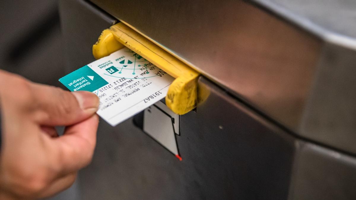 Una persona inserta una tarjeta en la máquina de validación del metro de Barcelona.
