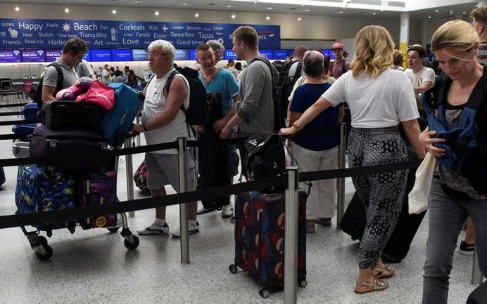 People queue with their luggage for the British ...