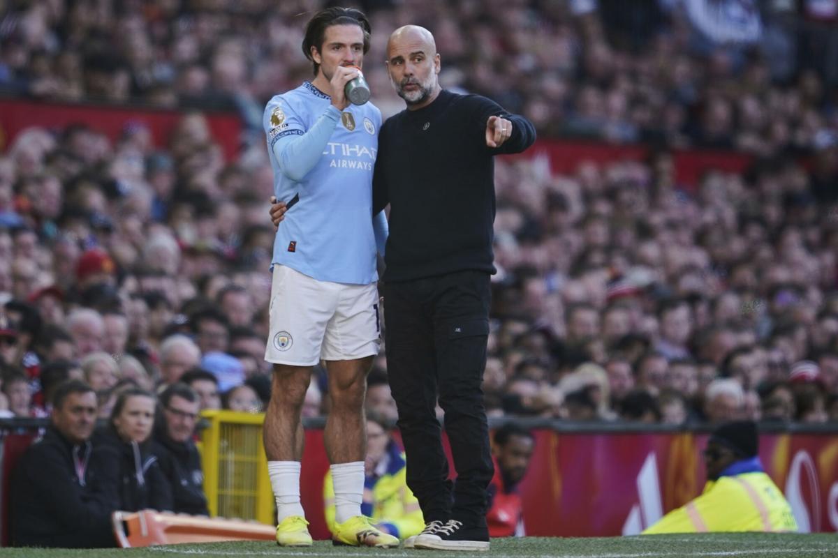 Manchester City's head coach Pep Guardiola talks to Jack Grealish during the English Premier League soccer match between Manchester City and Manchester United in Manchester, England, Sunday, April 6, 2025. (AP Photo/Dave Thompson)