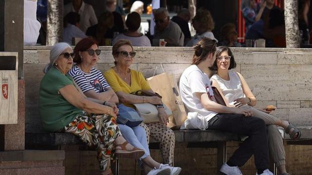 Varias mujeres sentadas en una zona sombreada de la plaza del Pilar para evitar el calor. | LAURA TRIVES