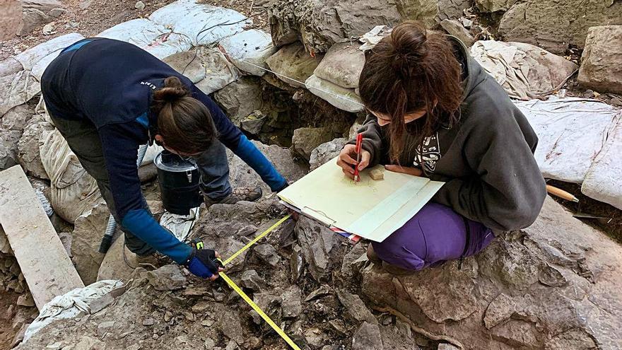 Dos arqueòlegs documentant les restes a la Bauma dels Fadrins.