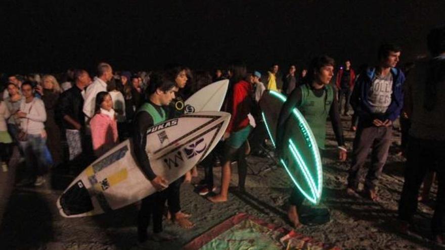 Varios surfistas, uno de ellos con tabla luminosa, ayer, antes de entrar al agua en Patos.  // Jorge Santomé