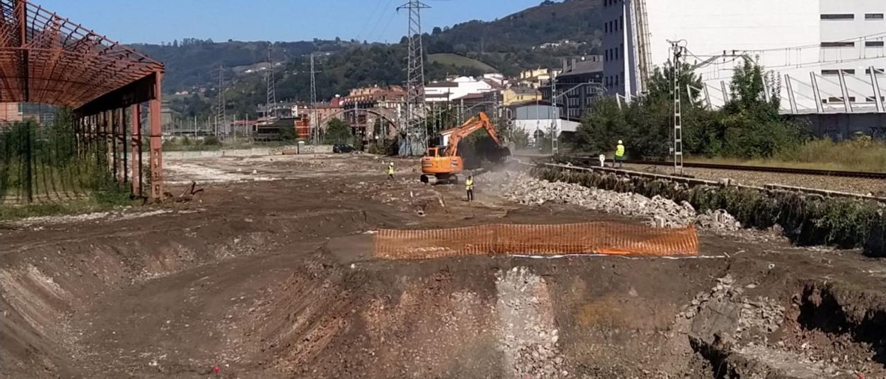 Una máquina trabajando en la parcela del futuro ferial de Talleres del Conde, con la vía a la derecha. | M. Á. G.