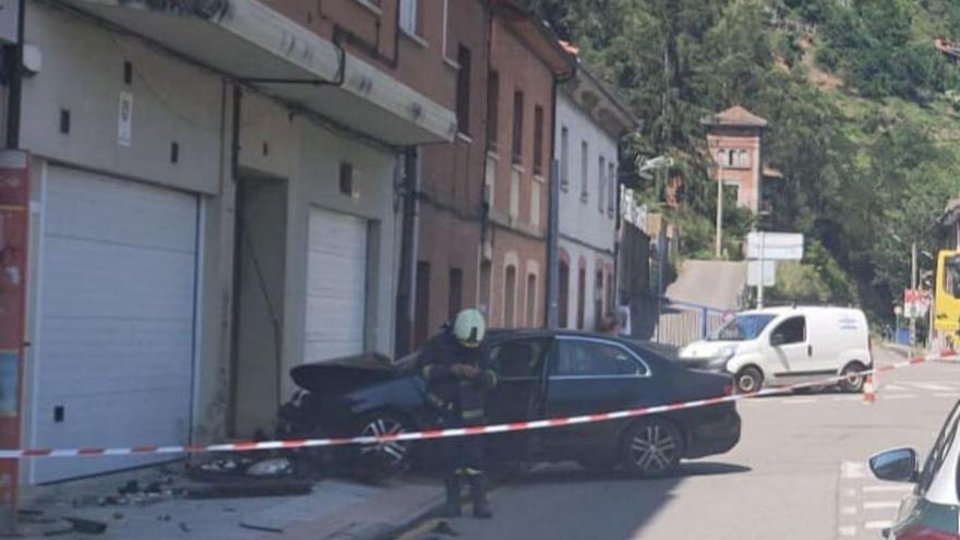 El coche que impactó contra la tubería de gas, con un bombero el primer término.