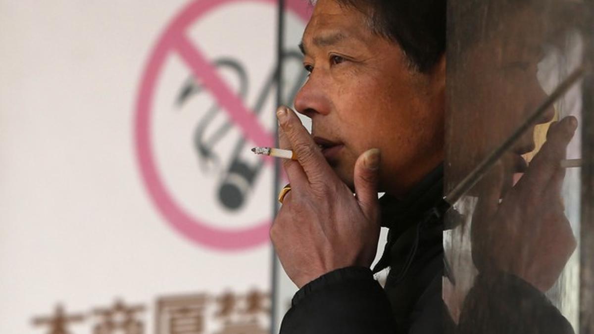 Un hombre fuma junto a un cartel que prohíbe fumar, en un centro comercial de Shangái, el pasado 10 de enero.