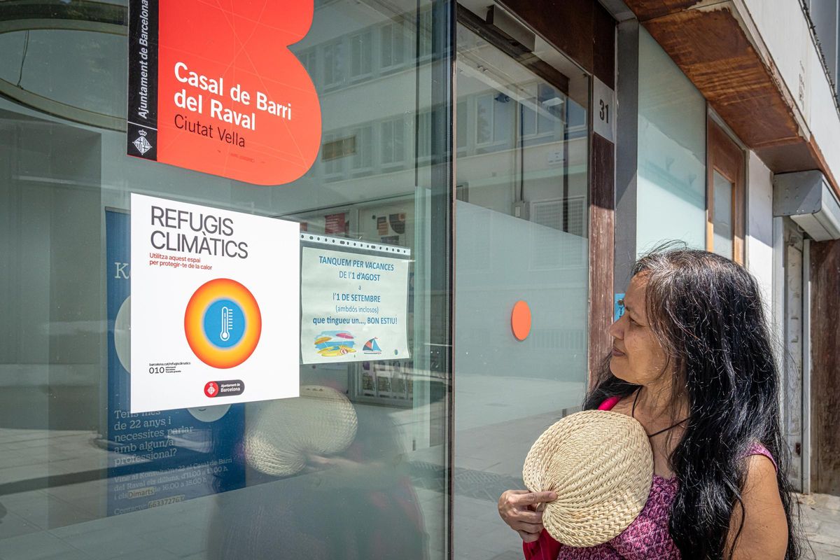 Una mujer observa el cartel acreditativo de un refugio climático en el Raval, en Barcelona.