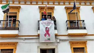 AOEX-Monesterio despliega una pancarta con un gran lazo rosa en la fachada del ayuntamiento
