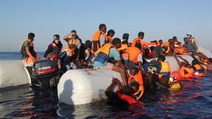 Un socorrista de la oenegé Proactiva Open Arms asiste a varios refugiados durante un rescate.