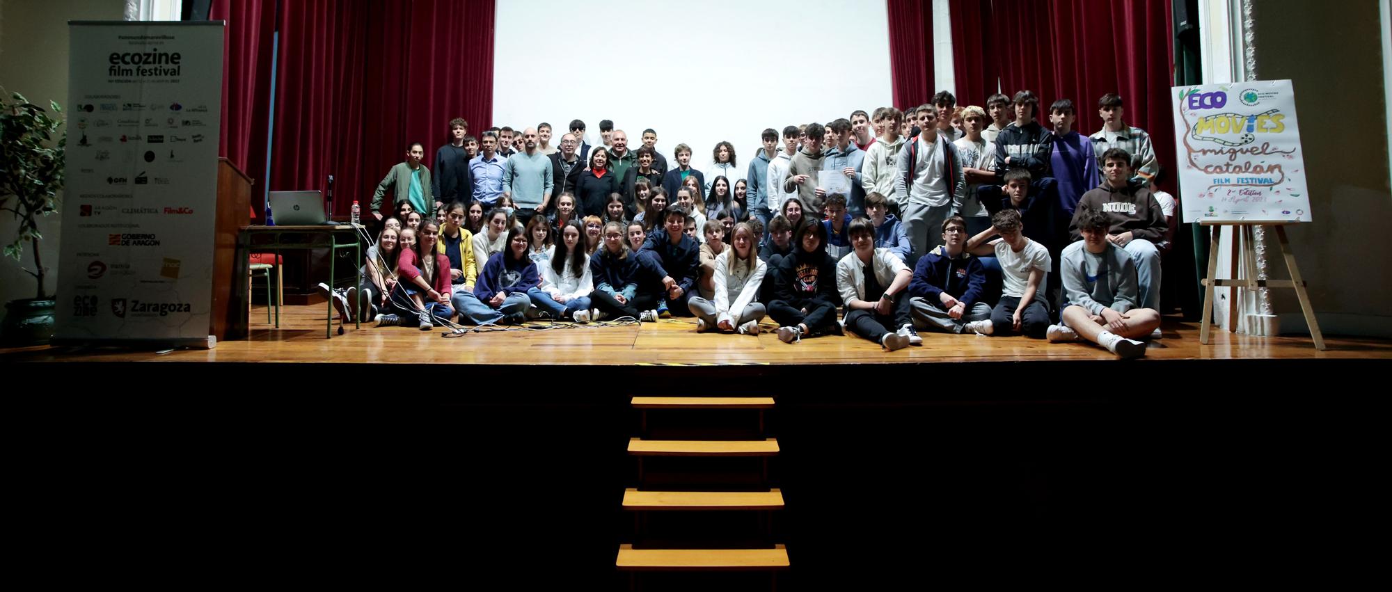 Participantes en el certamen sobre el escenario junto al cartel de la muestra.