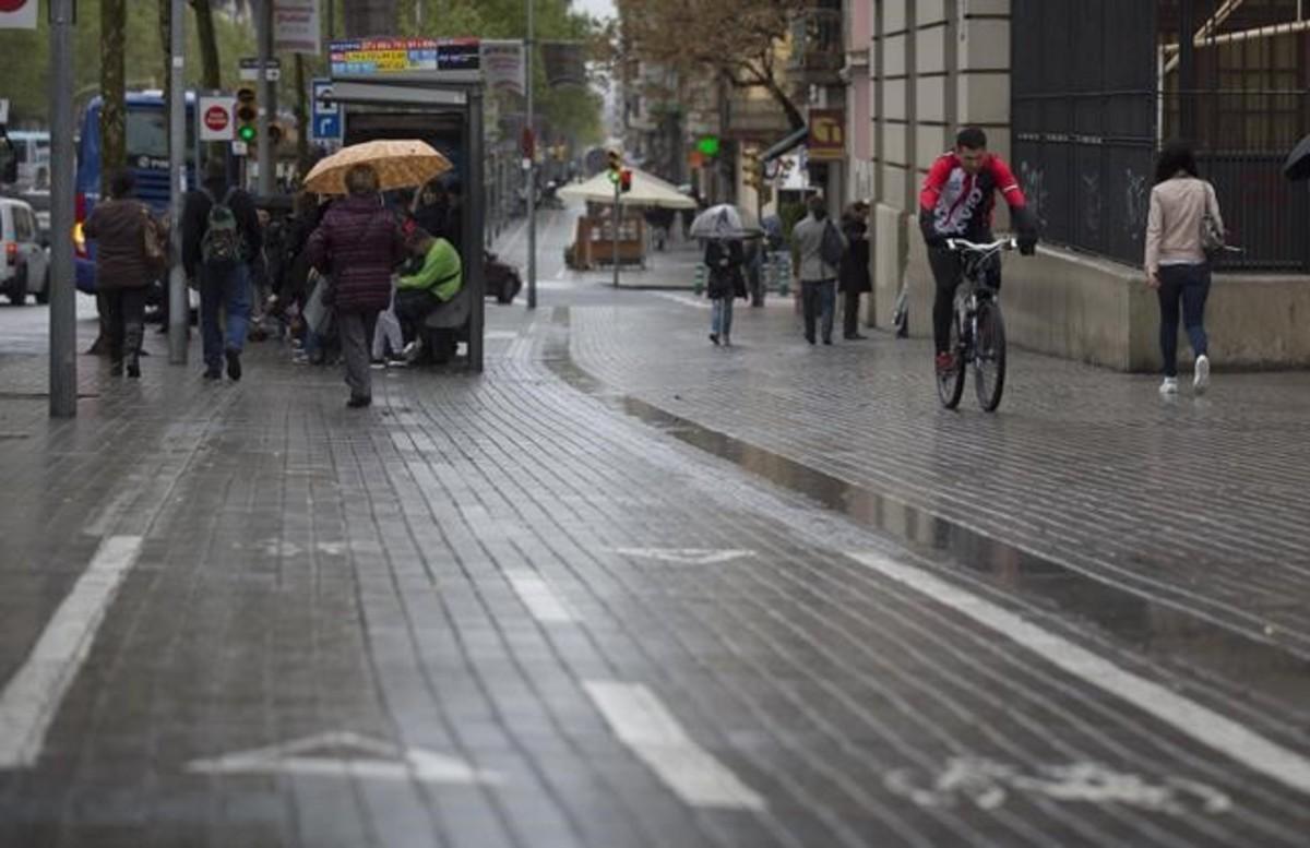 Un ciclista sortea una parada de bus instalada sobre el carril bus, en Gran Via.