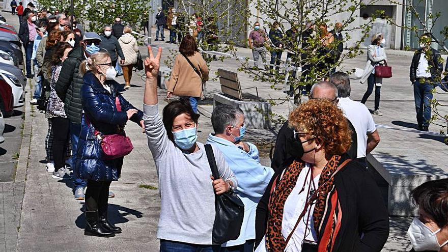 Una mujer hace el signo de la victoria en una de la colas para recibir la vacuna, ayer, en las inmediaciones de Expocoruña.  | // VÍCTOR ECHAVE