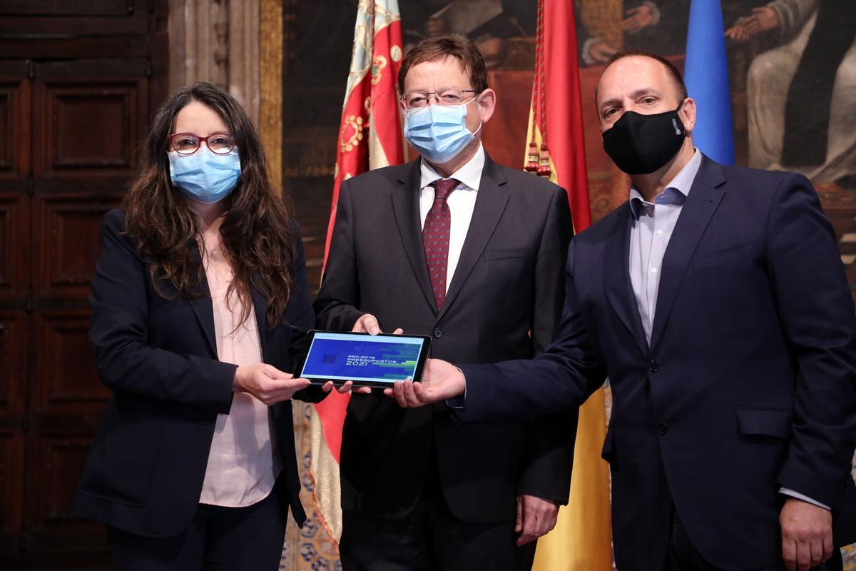 Mónica Oltra, Ximo Puig y Rubén Martínez Dalmau muestran una tablet con los Presupuestos de la Generalitat 2021.