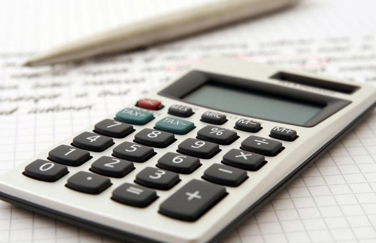 Bolígrafo, papeles y una calculadora preparada para calcular la base impositiva de ingresos provenientes de casinos online en España