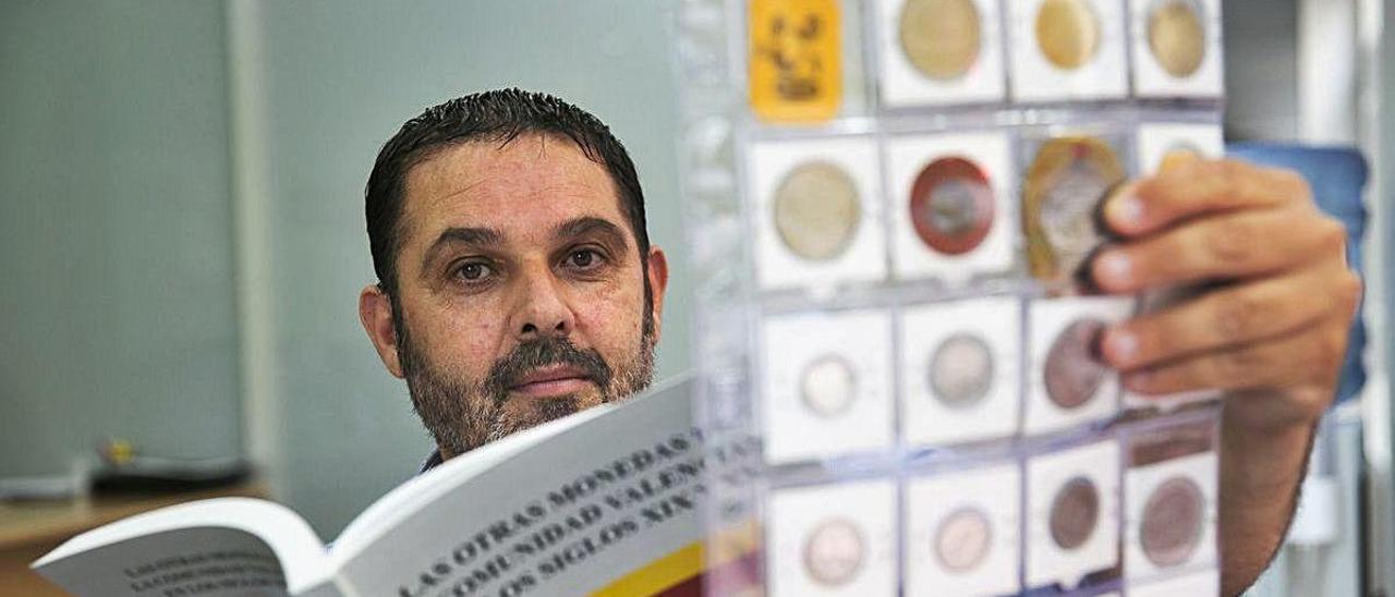 Luis Miguel Garrido muestra su libro y una parte de estas monedas.