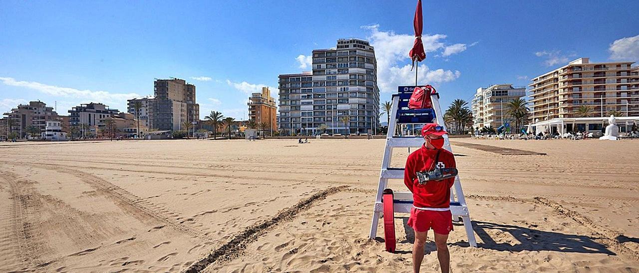 Un socorrista de la Cruz Roja en manga larga, en una de las postas de vigilancia de la playa de Gandia, completamente vacía, este mes de abril.   | LEVANTE-EMV