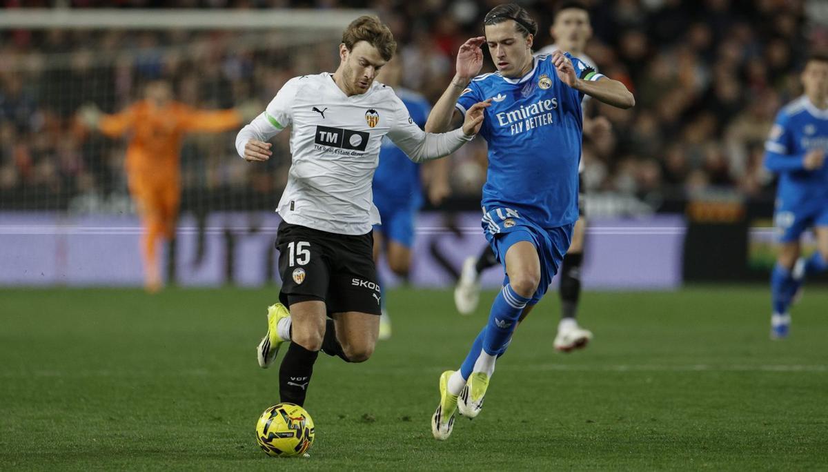 El delantero del Valencia Lucas Beltrán con el balón ante el defensa del Real Madrid Álvaro Carreras. | KAI FÖRSTERLING / EFE