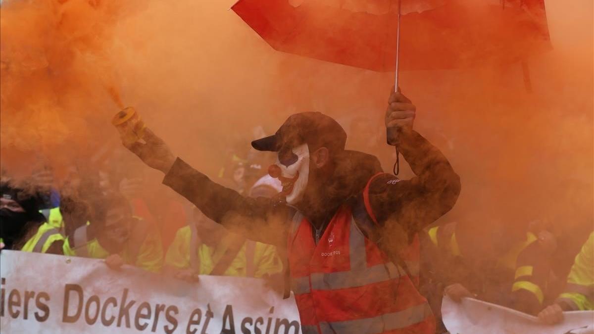 Un manifestante enciende una antorcha de humo durante la huelga contra las reformas del sistema de pensiones del Gobierno francés, este viernes, en Marsella.