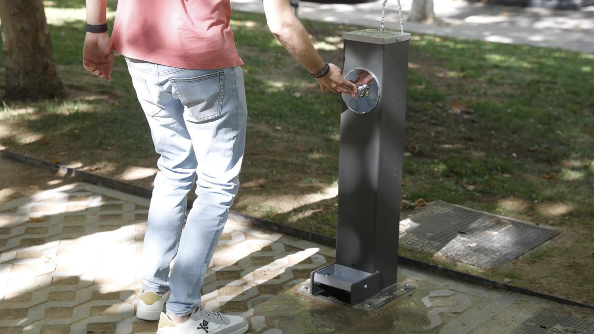 Una persona utiliza una de lass nuevas fuentes de agua potable instaladas por el Ayuntamiento de Madrid.