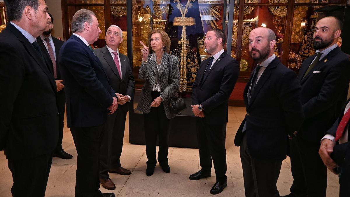 Doña Sofía atiende a las explicaciones de los archicofrades de la Esperanza durante su visita.