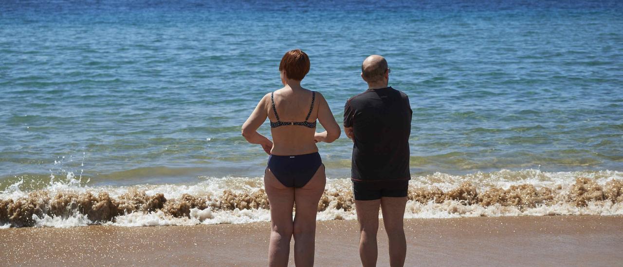 Dos bañistas miran hacia la costa en la playa de Las Teresitas, en Santa Cruz de Tenerife.