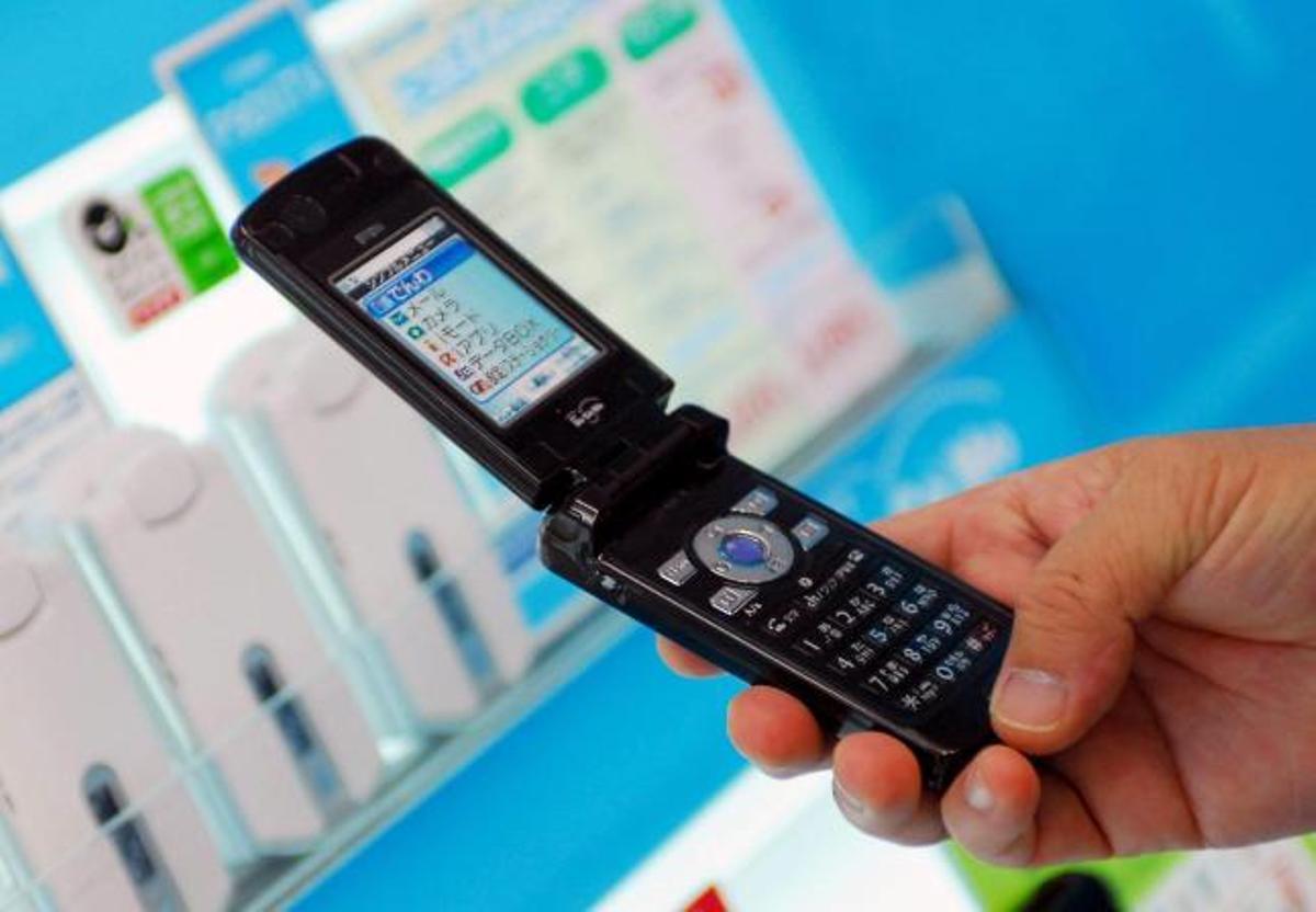 Un cliente sostiene un teléfono móvil en una tienda.