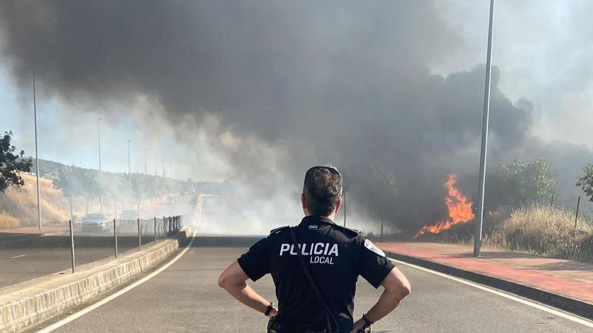 Un policía, en el carril cortado de la circunvalación sur por un fuego en Plasencia.