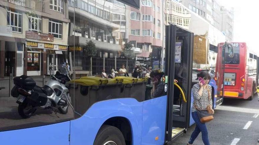 Un bus metropolitano deja a una viajera delante de un bus urbano.