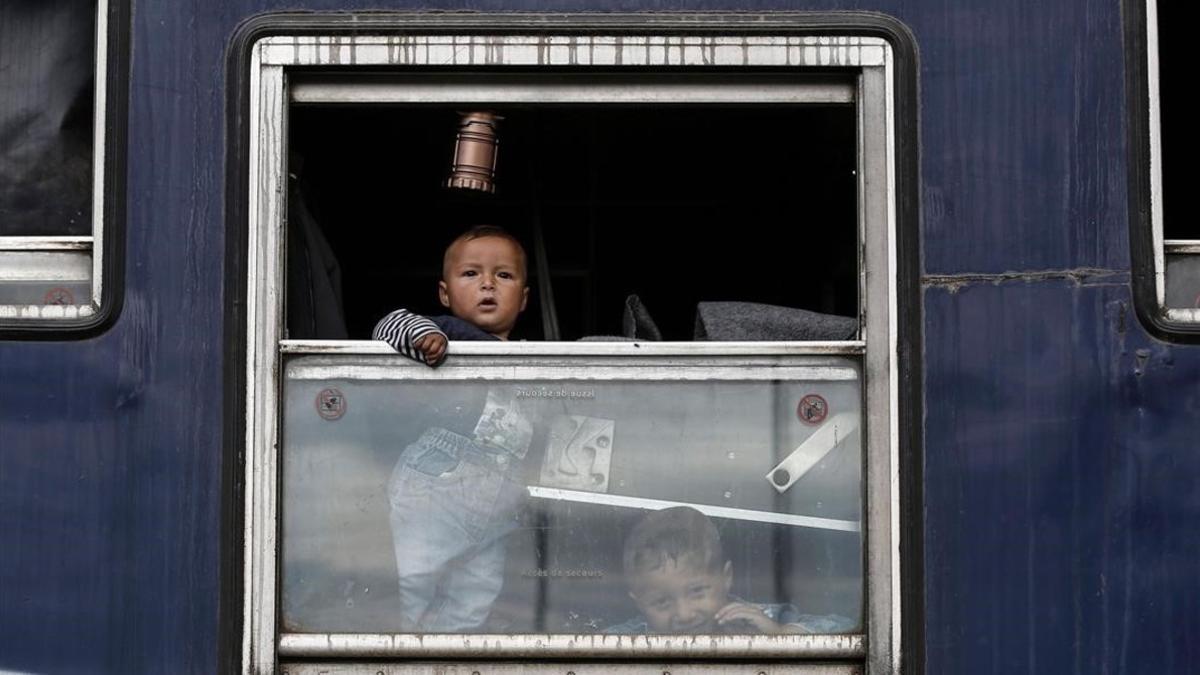 Dos niños esperan ser trasladados Idomeni a un centro de acogida.