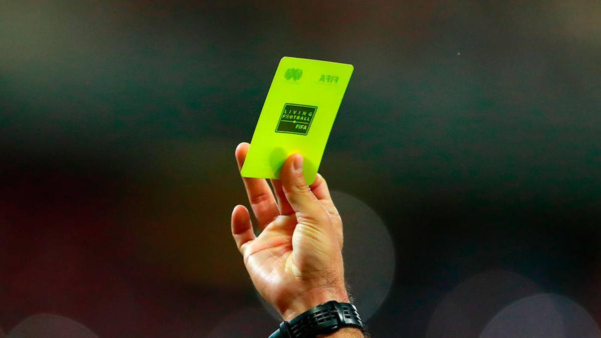 Un árbitro muestra una tarjeta amarilla durante un partido.