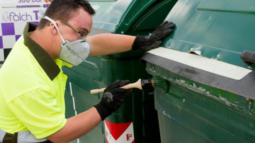 Un hombre con discapacidad pinta un contenedor de basura como parte de su ejercicio laboral.