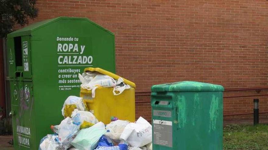 Basura acumulada junto a los contenedores de reciclaje.